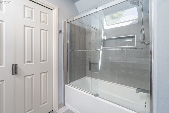 bathroom featuring a skylight and combined bath / shower with glass door