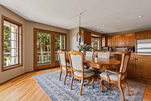 dining room with light wood-type flooring and a healthy amount of sunlight