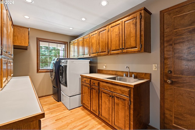 washroom with washing machine and clothes dryer, cabinets, sink, and light wood-type flooring