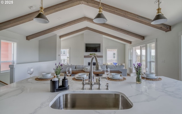 kitchen featuring sink, hanging light fixtures, and light stone countertops