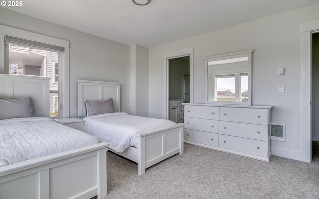 bedroom with connected bathroom and light colored carpet