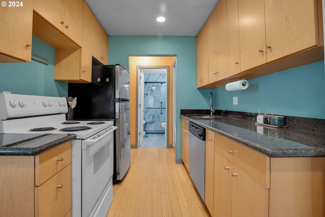 kitchen with dishwasher, white electric range oven, light wood-type flooring, dark stone counters, and sink