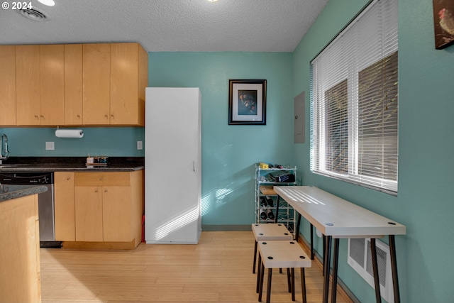 kitchen featuring a textured ceiling, light hardwood / wood-style floors, light brown cabinetry, and stainless steel dishwasher