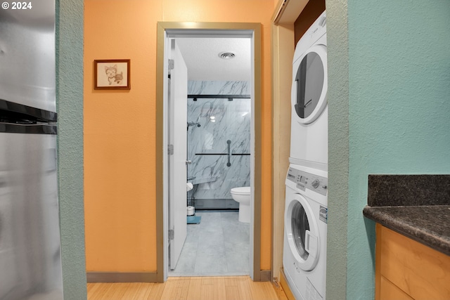 clothes washing area with light wood-type flooring and stacked washer / dryer