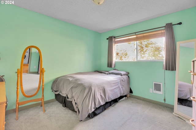 bedroom featuring a textured ceiling and light colored carpet