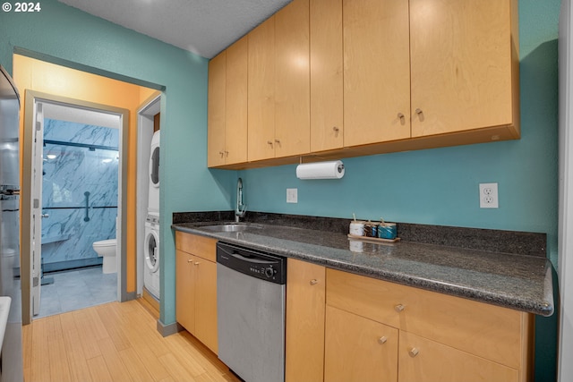 kitchen with sink, stacked washing maching and dryer, stainless steel dishwasher, and light wood-type flooring