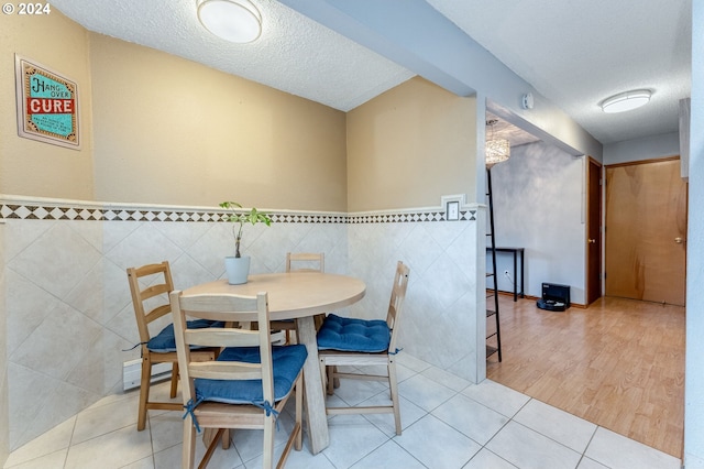 dining area with a textured ceiling, light tile patterned flooring, and tile walls