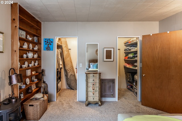 bedroom featuring heating unit, light carpet, a walk in closet, and a closet