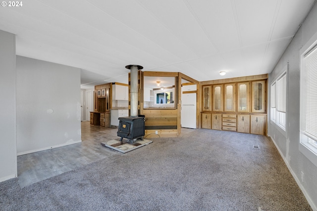 unfurnished living room featuring carpet and a wood stove