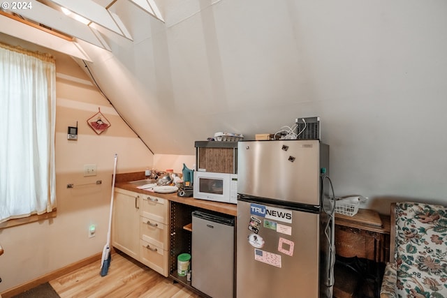 kitchen featuring wood counters, sink, refrigerator, light wood-type flooring, and stainless steel refrigerator