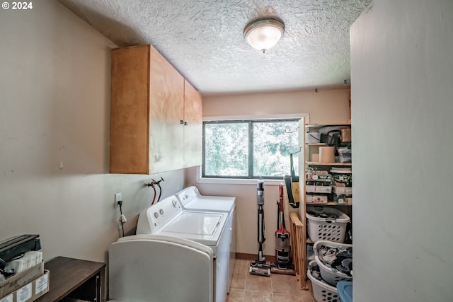 laundry room featuring cabinets, washing machine and dryer, a textured ceiling, and light tile patterned floors