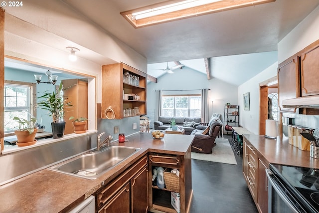 kitchen with ceiling fan, sink, lofted ceiling with skylight, and wall chimney range hood