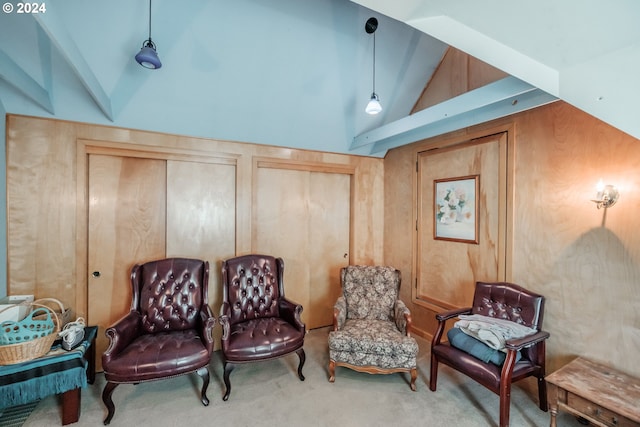 living area featuring high vaulted ceiling, wood walls, and carpet flooring