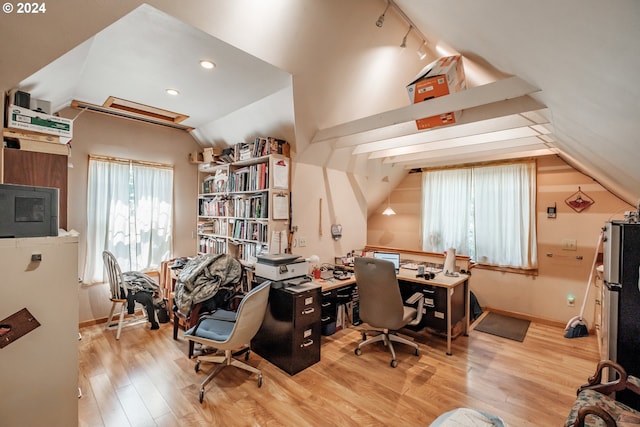 home office featuring lofted ceiling, track lighting, and light hardwood / wood-style flooring