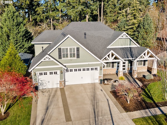 craftsman house featuring an attached garage, stone siding, a shingled roof, and concrete driveway