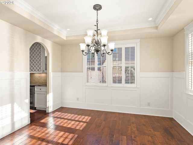 unfurnished dining area with a tray ceiling, arched walkways, wine cooler, a wealth of natural light, and dark wood-type flooring