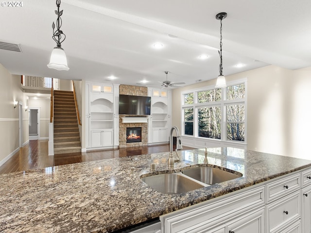 kitchen with dark stone counters, white cabinetry, a sink, and visible vents