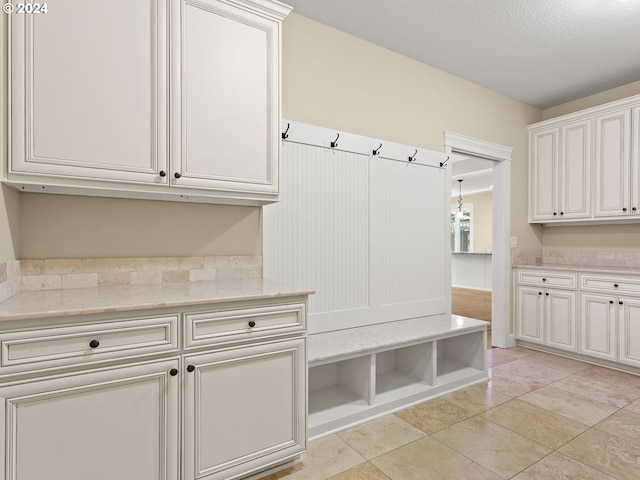 mudroom with light tile patterned floors and a textured ceiling