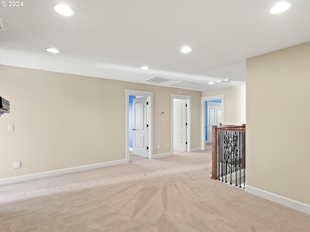 spare room with visible vents, light carpet, attic access, and recessed lighting