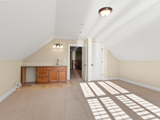 bonus room featuring light carpet, a sink, and baseboards