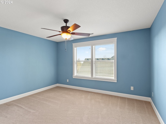 empty room with a textured ceiling, carpet flooring, a ceiling fan, and baseboards