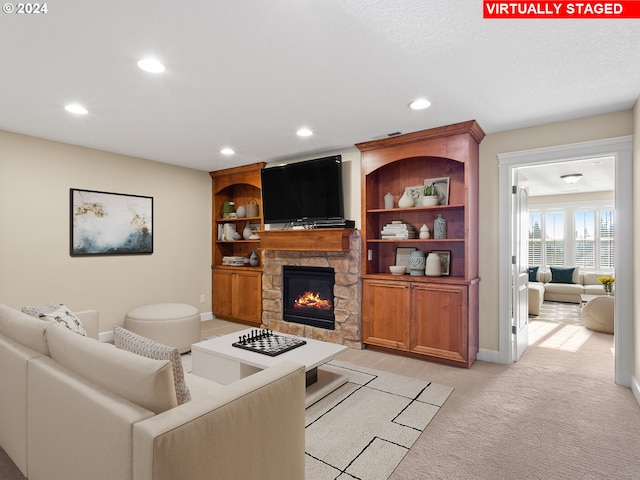 living area with recessed lighting, light colored carpet, a stone fireplace, and baseboards