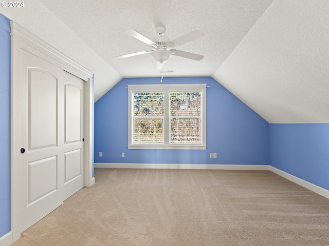 bonus room featuring light carpet, vaulted ceiling, a textured ceiling, and baseboards