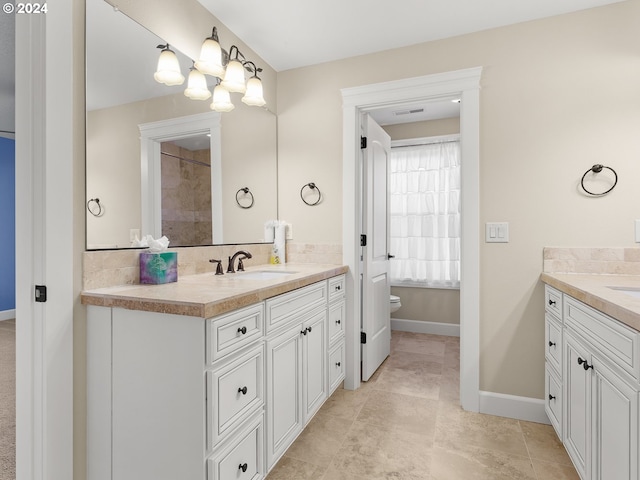 bathroom featuring visible vents, baseboards, two vanities, and a sink