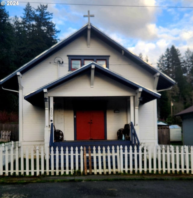 bungalow-style home with covered porch and a fenced front yard