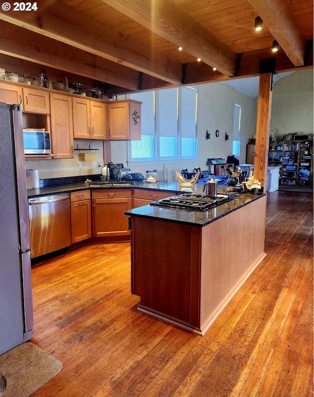 kitchen with beam ceiling, a sink, light wood-style floors, appliances with stainless steel finishes, and wooden ceiling