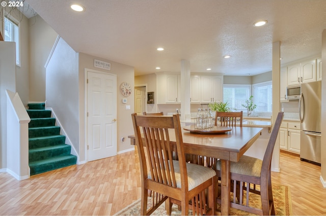 dining area with a textured ceiling and light wood-type flooring