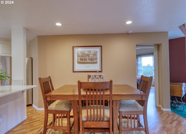 dining area featuring a textured ceiling and light wood-type flooring