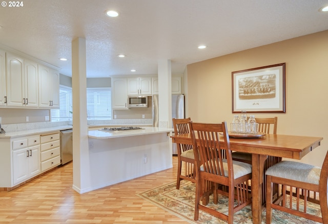 kitchen featuring white cabinets, appliances with stainless steel finishes, light wood-type flooring, and a textured ceiling