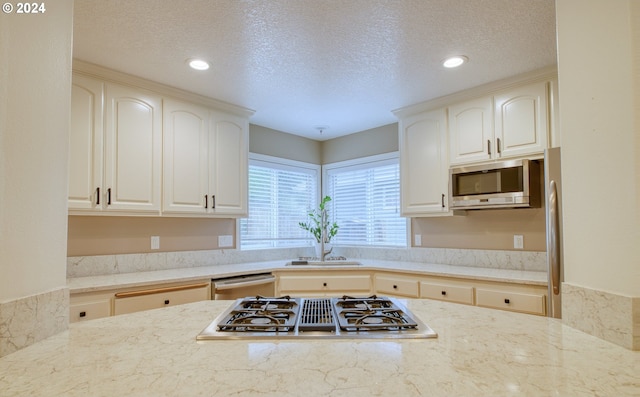 kitchen with light stone countertops, stainless steel appliances, and a textured ceiling