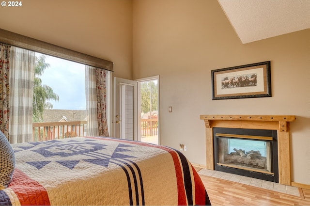 bedroom with a multi sided fireplace, multiple windows, access to exterior, and hardwood / wood-style flooring