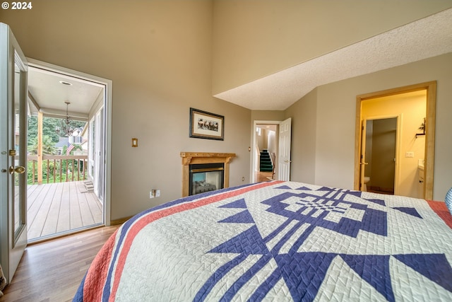 300 Spinnaker Way, Columbia City, OR 97018 - bedroom with access to exterior, wood finished floors, a glass covered fireplace, and a towering ceiling