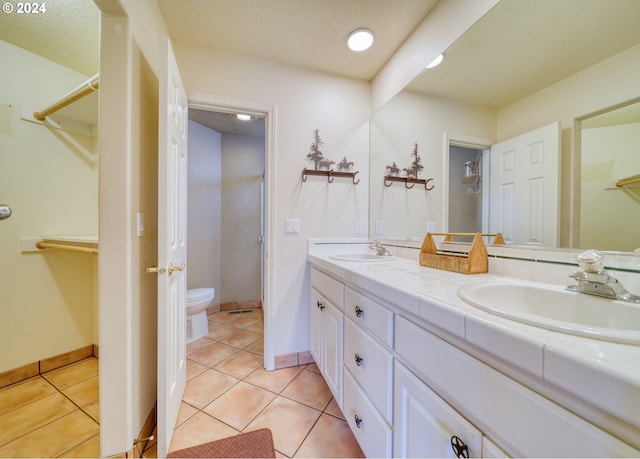 bathroom with tile patterned flooring, vanity, a textured ceiling, and toilet