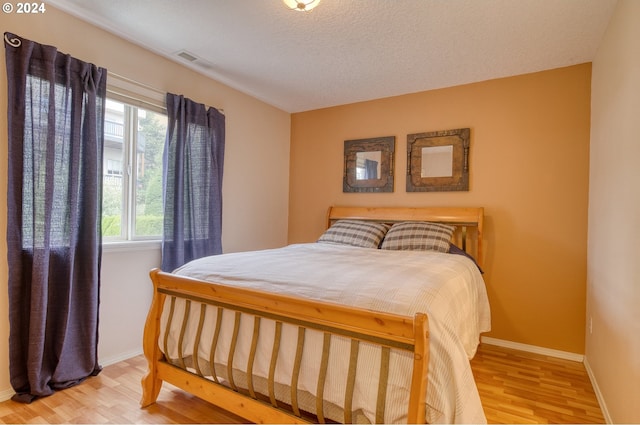 bedroom with a textured ceiling and hardwood / wood-style flooring