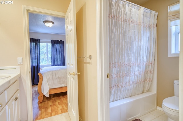 full bathroom with vanity, a textured ceiling, shower / bath combo with shower curtain, wood-type flooring, and toilet