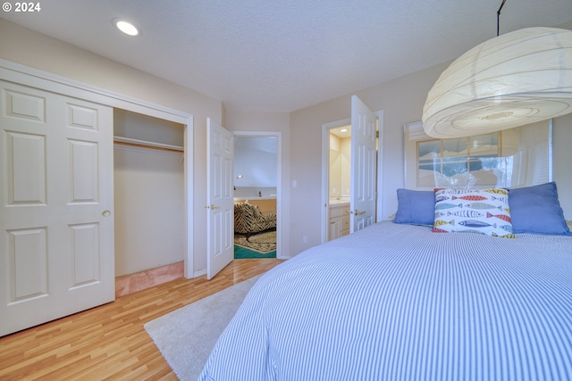 bedroom with hardwood / wood-style floors, ensuite bath, and a closet