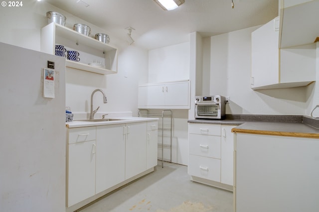 300 Spinnaker Way, Columbia City, OR 97018 - kitchen featuring a sink, open shelves, finished concrete floors, white cabinetry, and freestanding refrigerator