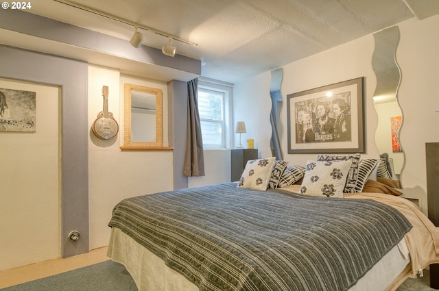 bedroom with carpet, a textured ceiling, and track lighting