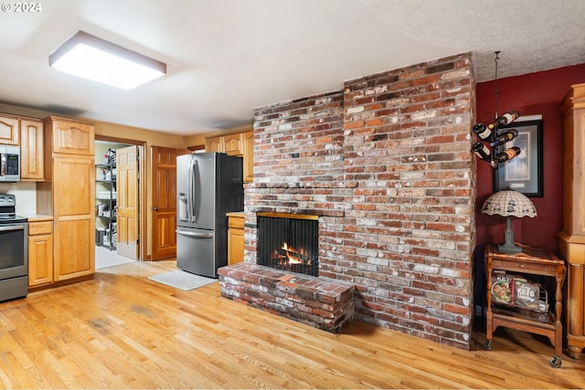8805 NE 36th St, Vancouver, WA 98662 - kitchen with light wood finished floors, a fireplace, light countertops, and appliances with stainless steel finishes