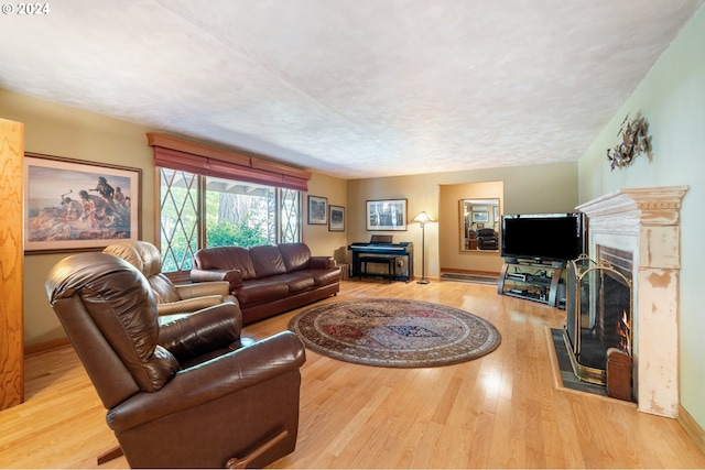8805 NE 36th St, Vancouver, WA 98662 - living room featuring a warm lit fireplace, baseboards, a textured ceiling, and wood finished floors