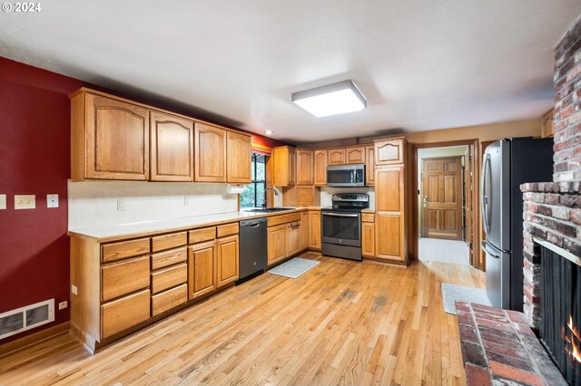 8805 NE 36th St, Vancouver, WA 98662 - kitchen featuring a sink, a fireplace, appliances with stainless steel finishes, light wood-style flooring, and visible vents