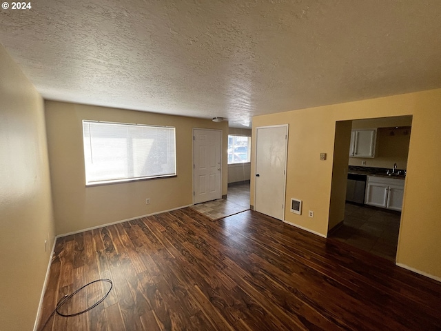 empty room with sink, dark hardwood / wood-style floors, and a textured ceiling