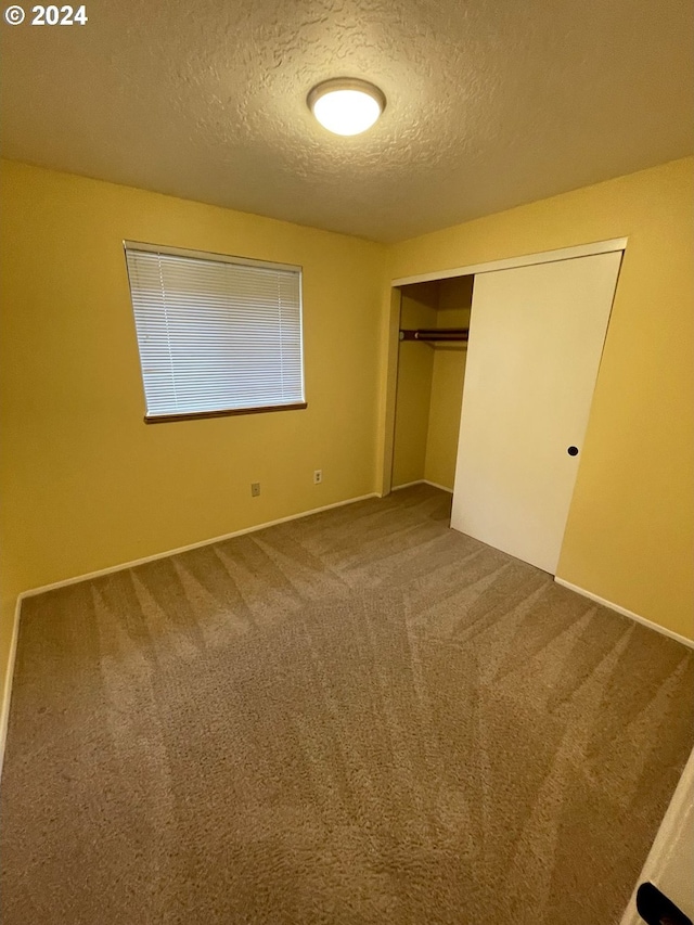 unfurnished bedroom featuring a closet, a textured ceiling, and carpet floors