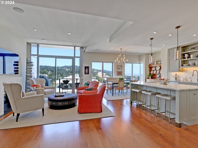 living room featuring an inviting chandelier, light hardwood / wood-style flooring, and sink