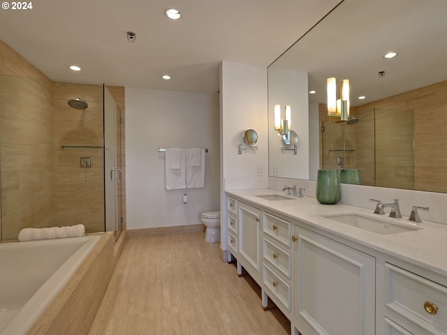 bathroom featuring toilet, a stall shower, double vanity, and a sink