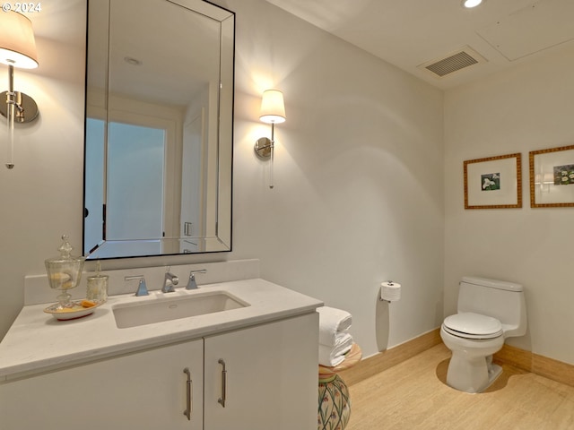 bathroom with toilet, visible vents, wood finished floors, and vanity